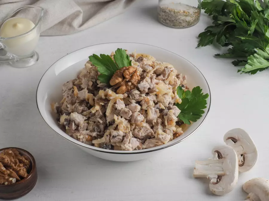 Готовое блюдо салат с курицей, грибами, сыром и грецкими орехами