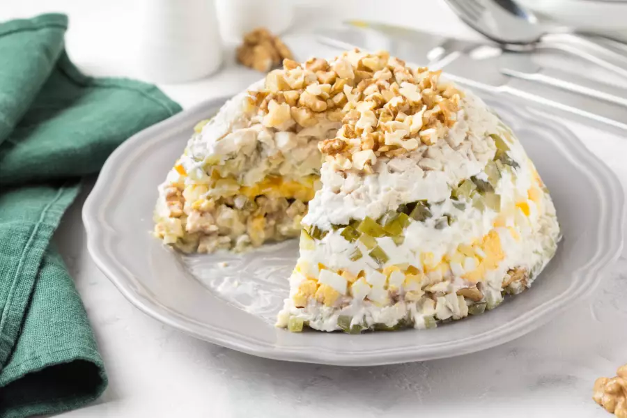Готовое блюдо слоёный салат с курицей, огурцом, яйцом и грецким орехом